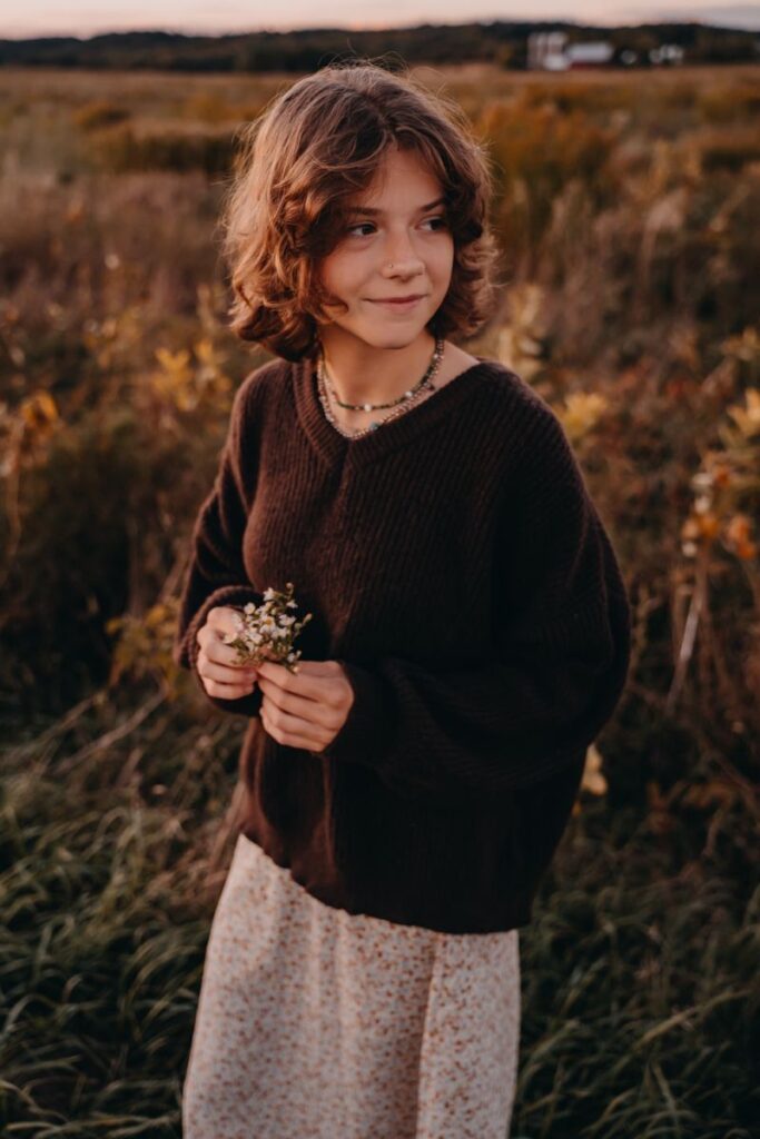 Girl with bob in field with brown sweater on